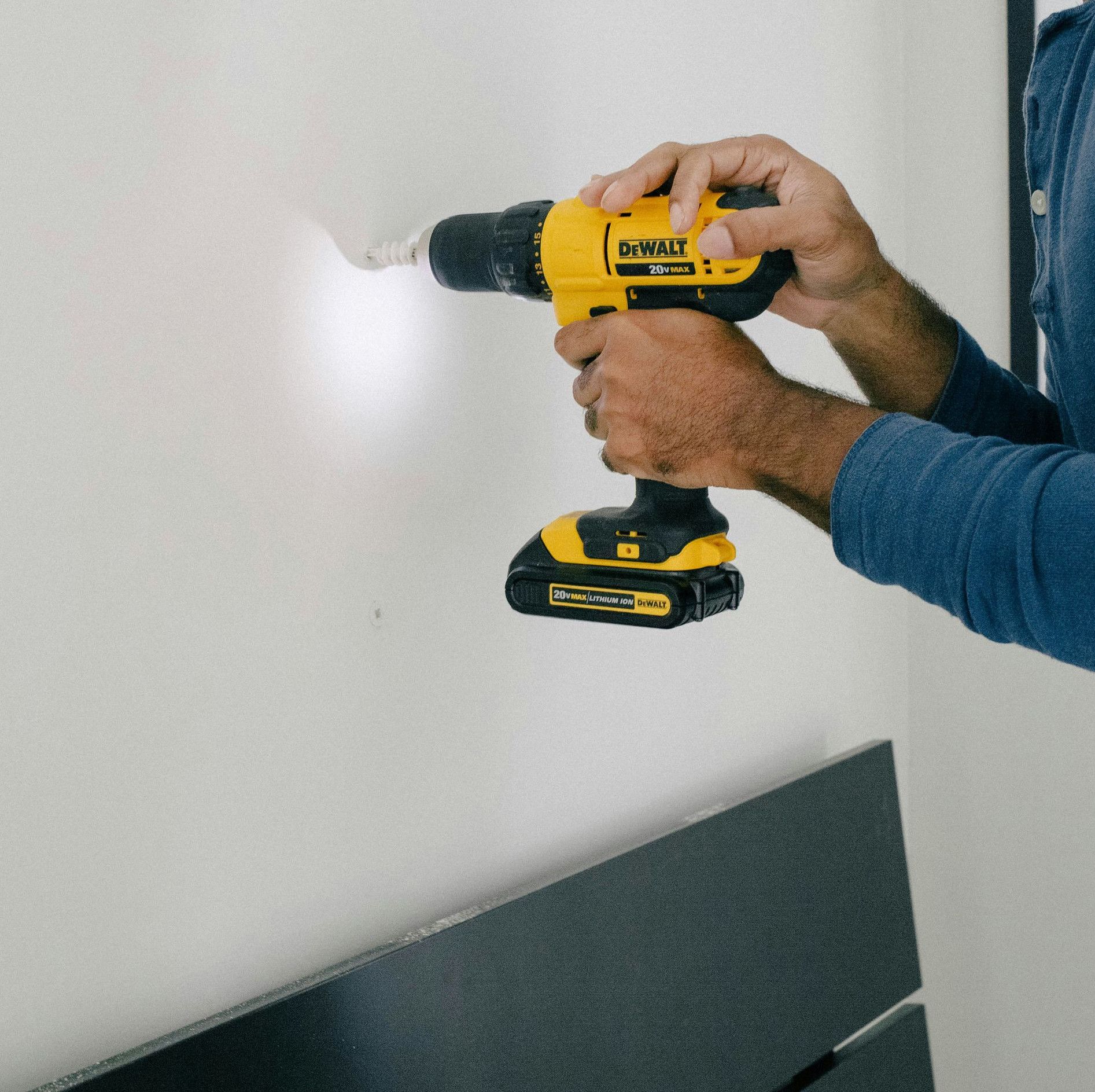 person holding yellow and black cordless hand drill